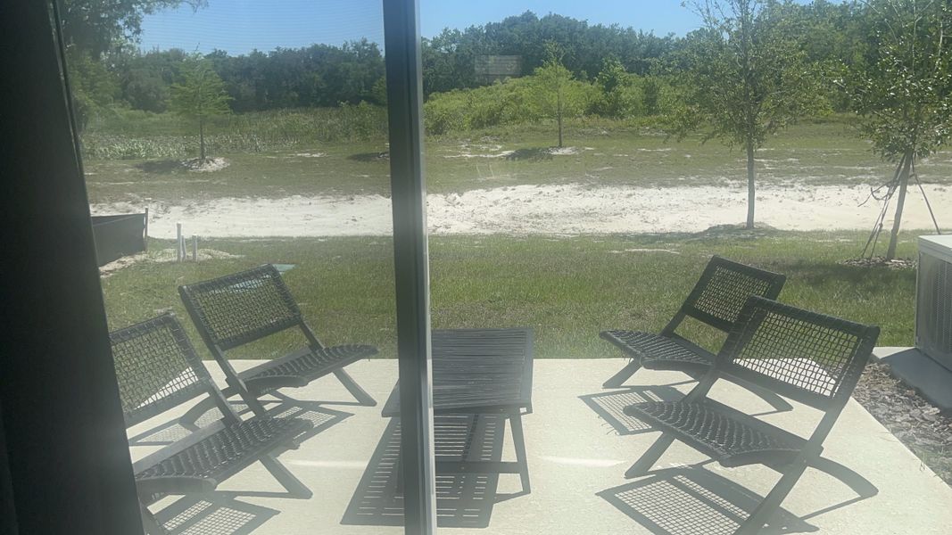 A cozy patio with sleek black chairs overlooking a lush, serene landscape.