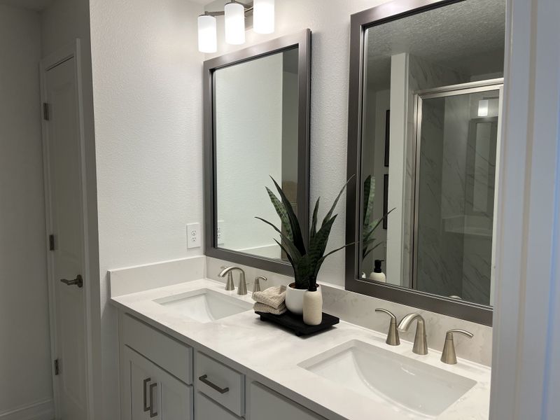 A modern bathroom with dual sinks, sleek fixtures, large mirrors, and elegant lighting.