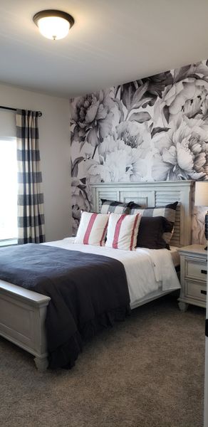 A cozy bedroom with floral accent wall, plaid curtains, and plush bedding in a neutral palette. A cozy bedroom with floral accent wall, plaid curtains, and plush bedding in a neutral palette.