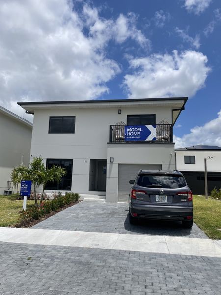 A sleek modern home with a paved driveway and balcony in On Alba by Onx Homes (Florida City, FL).