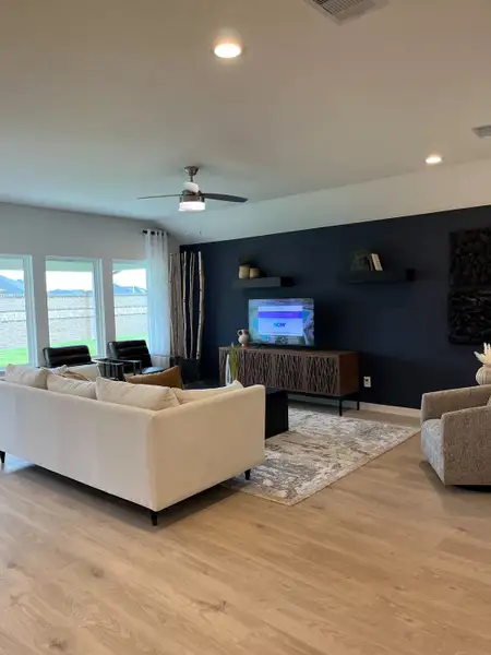 A contemporary living room featuring a sleek white sofa, dark accent wall, and modern decor with ample natural light.