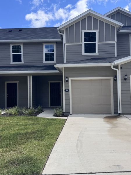 A modern gray townhouse with a neat driveway and lawn in Orchard Park Townhomes by KB Home (St. Augustine, FL).