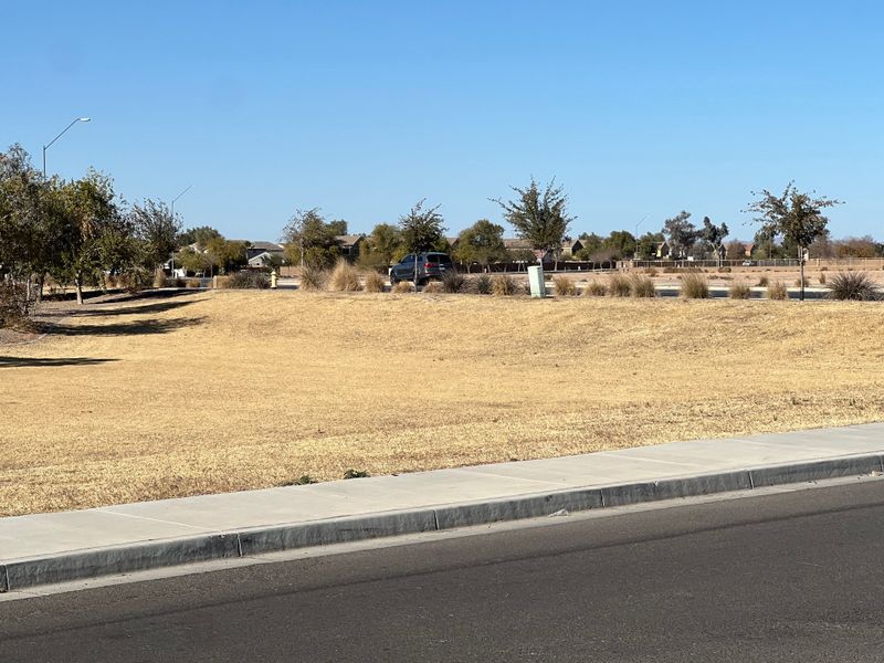 A serene neighborhood landscape with open green spaces in Tortosa by KB Home (Maricopa, AZ).