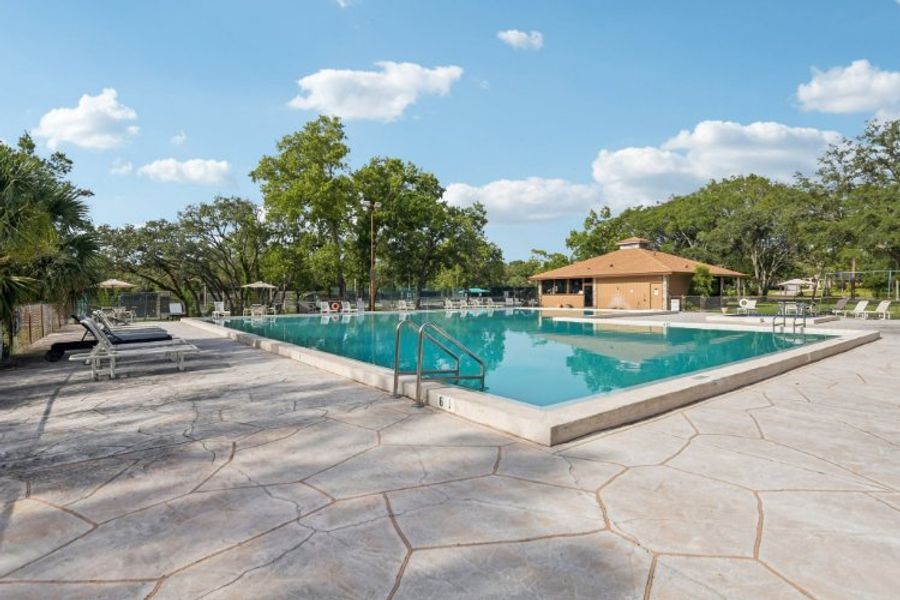 A swimming pool with trees and a building in the background.