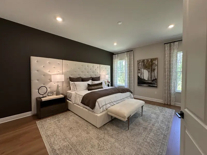 Luxurious bedroom featuring a tufted headboard, elegant nightstands, and large windows with serene views.
