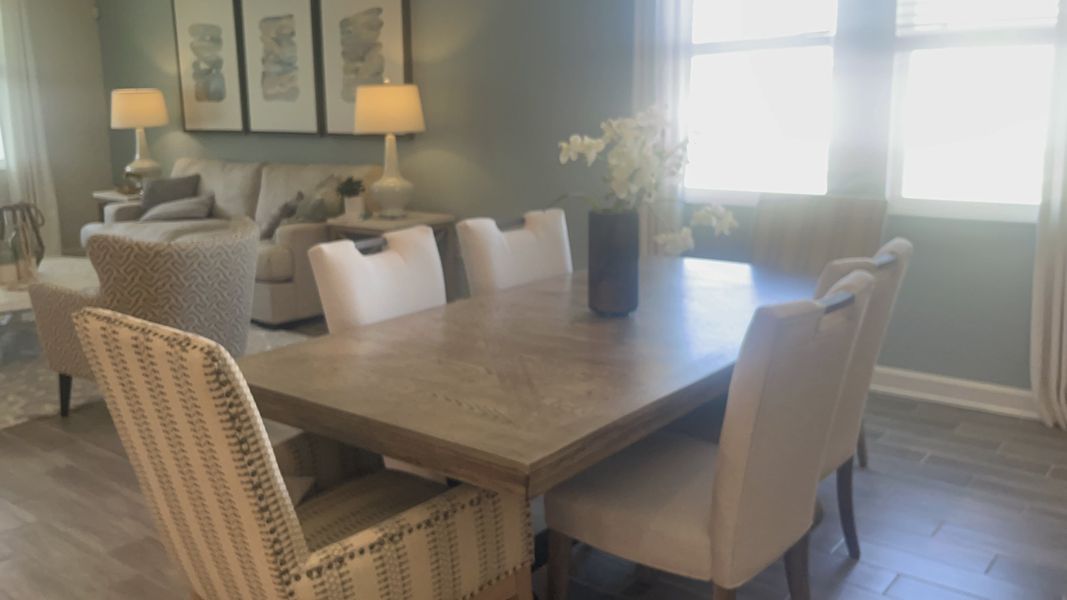 A cozy dining area with a wooden table, upholstered chairs, and soft lighting, adjacent to a comfortable living space.