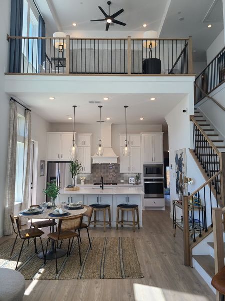 A spacious kitchen and dining area with a loft, highlighting modern lighting, island seating, and stylish decor. A spacious kitchen and dining area with a loft, highlighting modern lighting, island seating, and stylish decor.