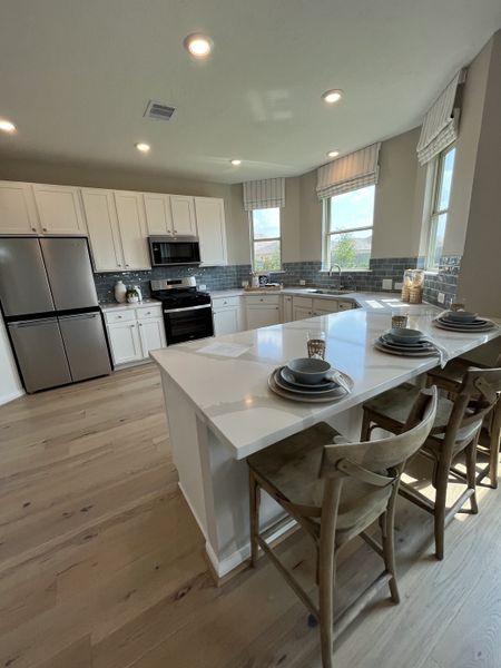 A bright kitchen with white cabinetry, sleek appliances, and a spacious island with seating, perfect for entertaining.