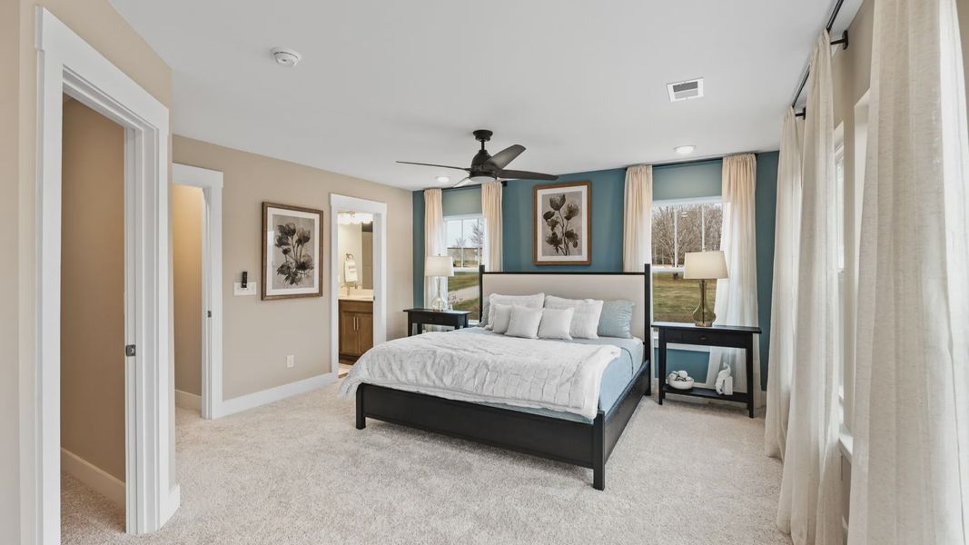 Spacious primary suite with modern decor, large windows, and plush carpet in two story townhome at Hickory Heights