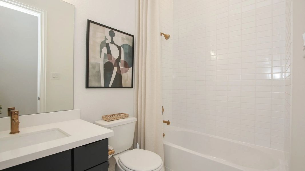 Sophisticated white tiling and brass fixtures in a luxurious Coastal Point bathroom reflect modern elegance.