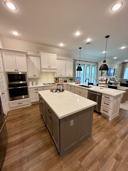 A spacious kitchen with quartz countertops, dual islands, white cabinetry, and stylish pendant lighting.