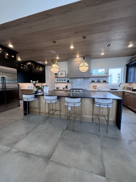 A modern kitchen with a spacious island, stylish barstools, pendant lighting, and sleek appliances.