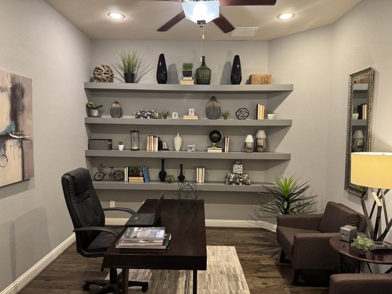 A chic home office with sleek shelving, decorative vases, and a modern desk, complemented by cozy seating and stylish lighting.