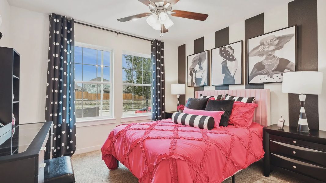 Simpson Crossing's bedroom features chic pink bedding, striped wall art, and elegant polka dot accents.