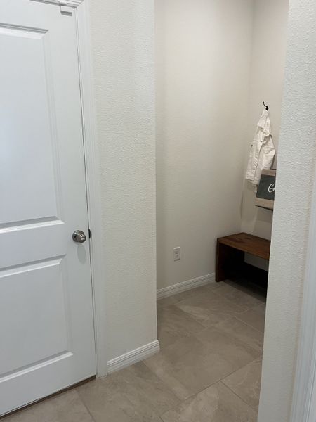 A cozy entryway nook with tiled flooring, a wooden bench, and crisp white walls, perfect for everyday organization.