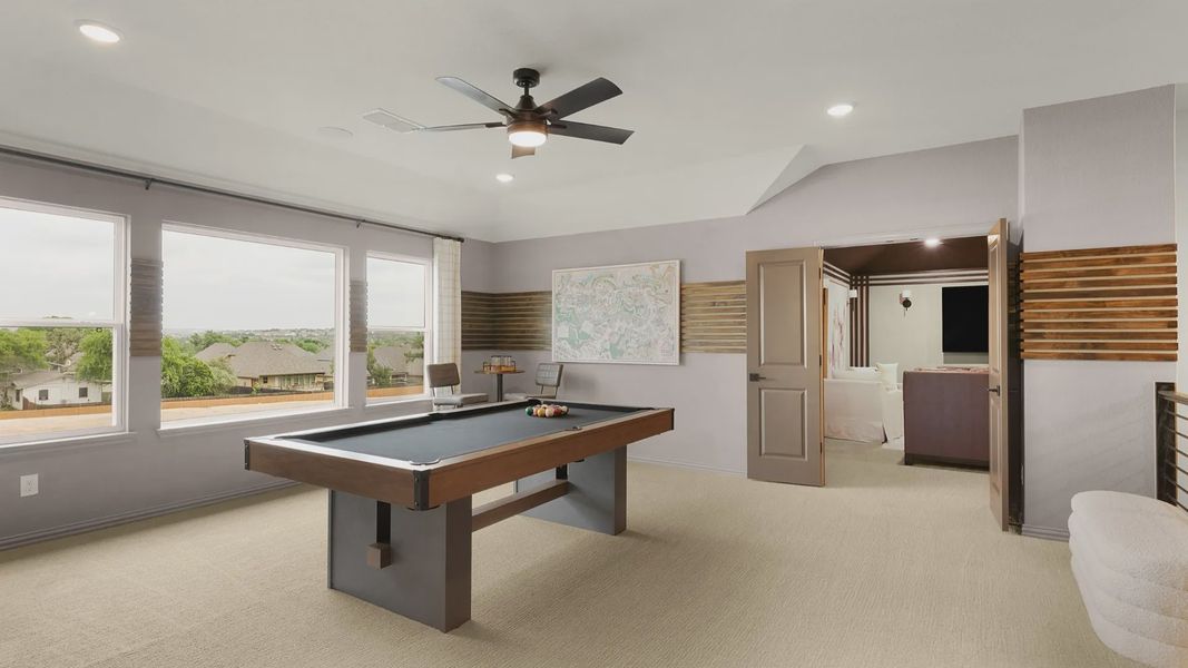 Second-floor game room with large windows and a ceiling fan, connected to a dedicated media room for entertainment.