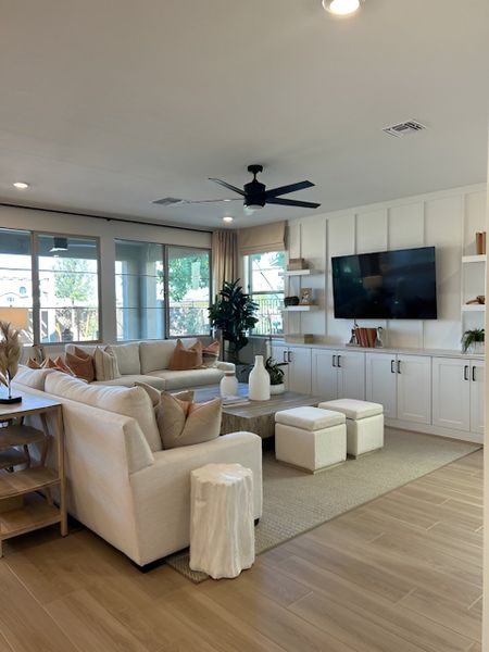 A stylish, open-concept living room with a sectional sofa, built-in cabinets, and large windows allowing natural light.