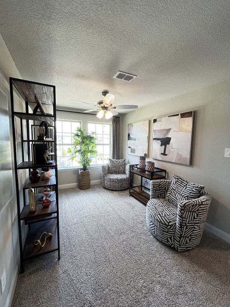 A cozy room featuring patterned armchairs, stylish shelving, abstract art, and a large window for ample natural light. A cozy room featuring patterned armchairs, stylish shelving, abstract art, and a large window for ample natural light.