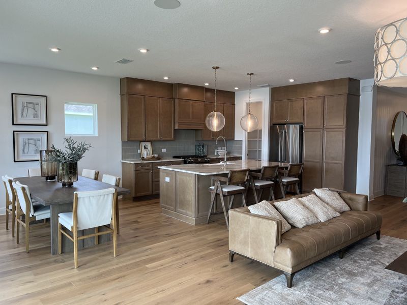 A chic open-concept kitchen with wooden cabinets, pendant lights, and an elegant dining area.