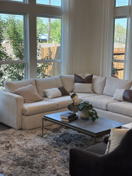 A cozy living room with a plush sectional, modern coffee table, and large windows providing ample natural light.