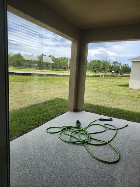 A serene patio with a green garden hose overlooking lush greenery, offering a peaceful retreat.