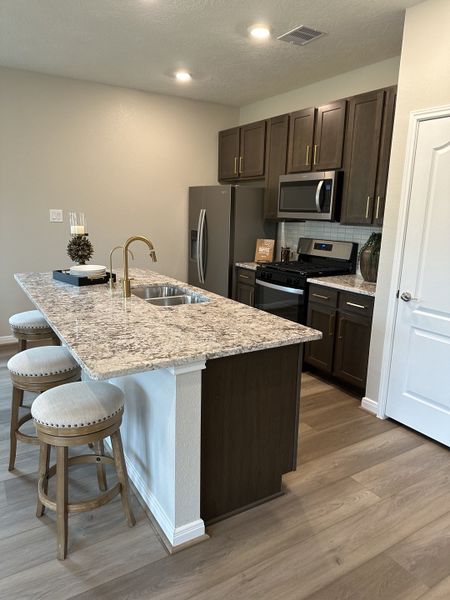 A modern kitchen featuring a granite island with bar seating, sleek dark cabinets, and stainless steel appliances. A modern kitchen featuring a granite island with bar seating, sleek dark cabinets, and stainless steel appliances.