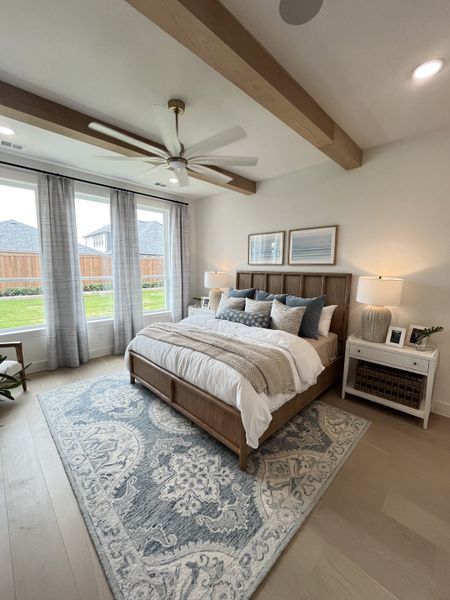 A cozy bedroom featuring wood beams, soft lighting, and a plush patterned rug under the bed. A cozy bedroom featuring wood beams, soft lighting, and a plush patterned rug under the bed.