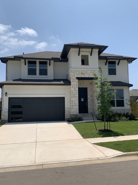 A modern two-story home with a sleek design and landscaped yard in Oaks at San Gabriel by Brightland Homes (Georgetown, TX).