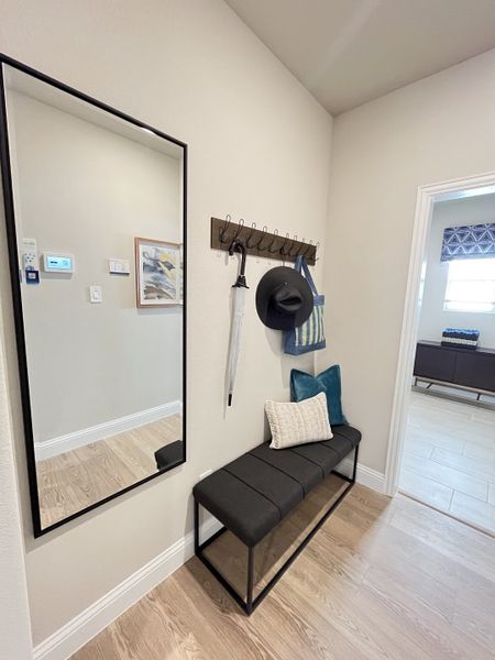 A cozy entryway with a sleek mirror, cushioned bench, and stylish coat hooks, blending modern and functional design elements.