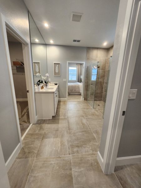 A modern bathroom with sleek vanity, large mirror, and elegant tile flooring.