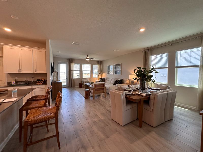 A modern open-concept living space with elegant wood floors, cozy seating, and abundant natural light.