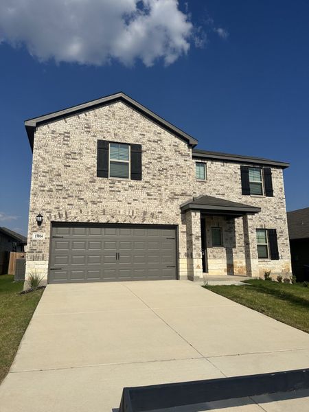 A beautiful brick home with a spacious driveway and classic shutters in Autry Pond by Meritage Homes (San Antonio, TX).