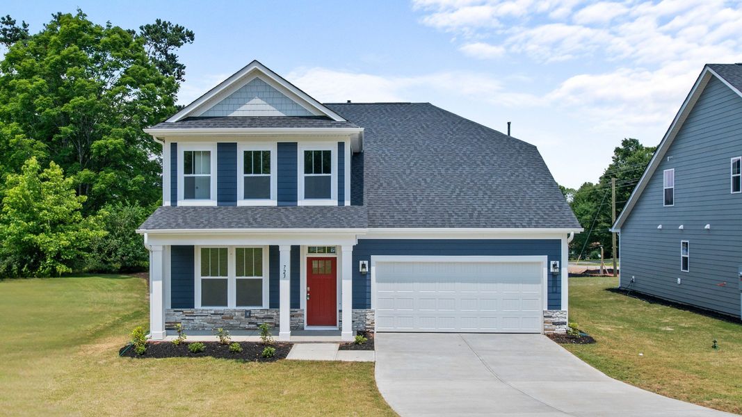 Two story home in Greenville, SC with neutral exterior, two car garage, and stone columns at Pelham Crossing by DRB Homes