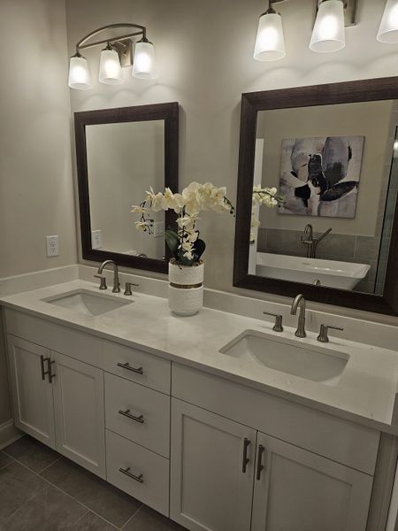 A modern bathroom featuring dual sinks, elegant mirrors, soft lighting, and a sleek white vanity for a sophisticated touch.
