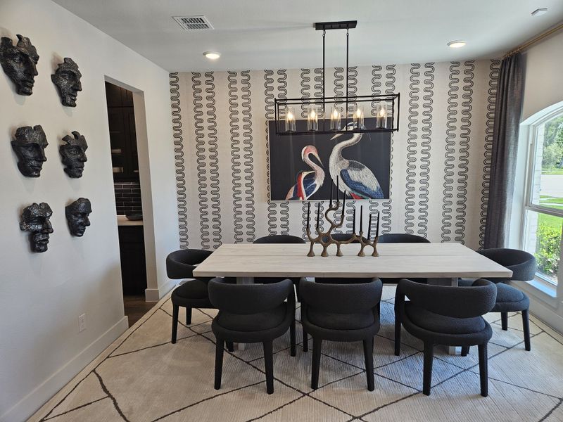 A chic dining room with wall art, sculptural décor, patterned wallpaper, and modern pendant lighting. A chic dining room with wall art, sculptural décor, patterned wallpaper, and modern pendant lighting.
