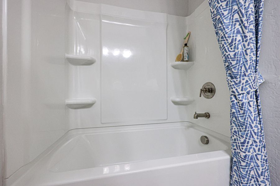 A bathroom with a bathtub and shower curtain. A bathroom with a bathtub and shower curtain.