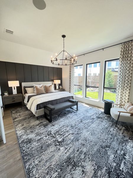 A chic bedroom with a textured rug, modern chandelier, and large windows offering natural light. A chic bedroom with a textured rug, modern chandelier, and large windows offering natural light.
