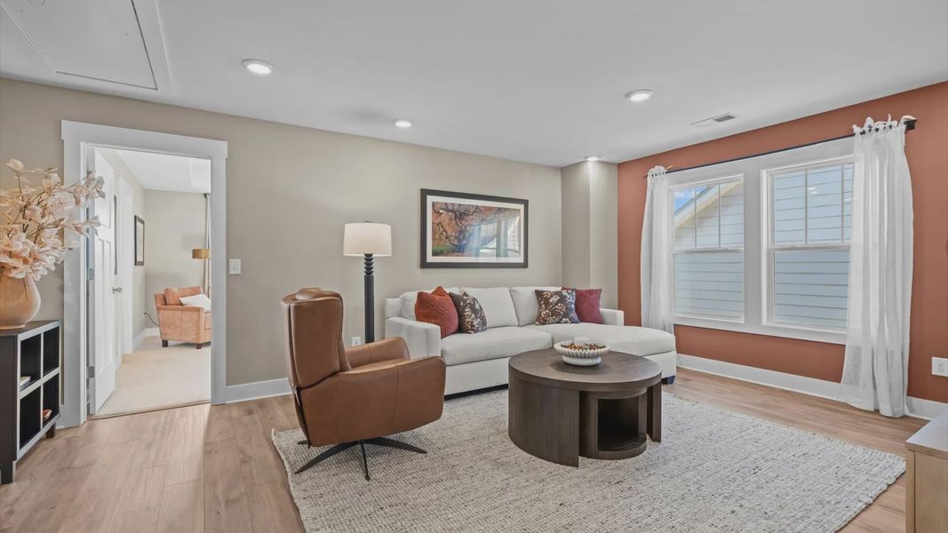 Upstairs loft space with cozy, inviting feel with hardwood flooring and large bay window at Pelham Crossing by DRB Homes