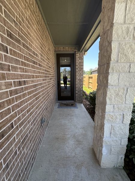 A charming brick entryway with a modern glass door in Wedgewood Forest by LGI Homes (Conroe, TX).