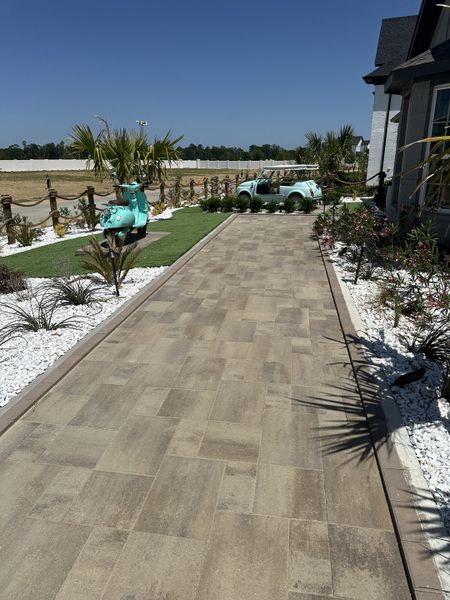 A charming driveway with a vintage vibe in Saint Tropez by Megatel Homes, surrounded by greenery and modern landscaping (Huffman, TX). A charming driveway with a vintage vibe in Saint Tropez by Megatel Homes, surrounded by greenery and modern landscaping (Huffman, TX).
