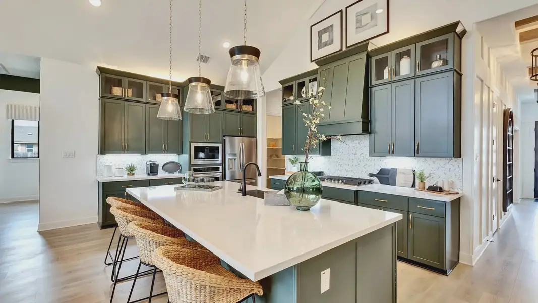 Elegant quartz countertops and distinctive green cabinetry enrich this Hawkes Landing kitchen.