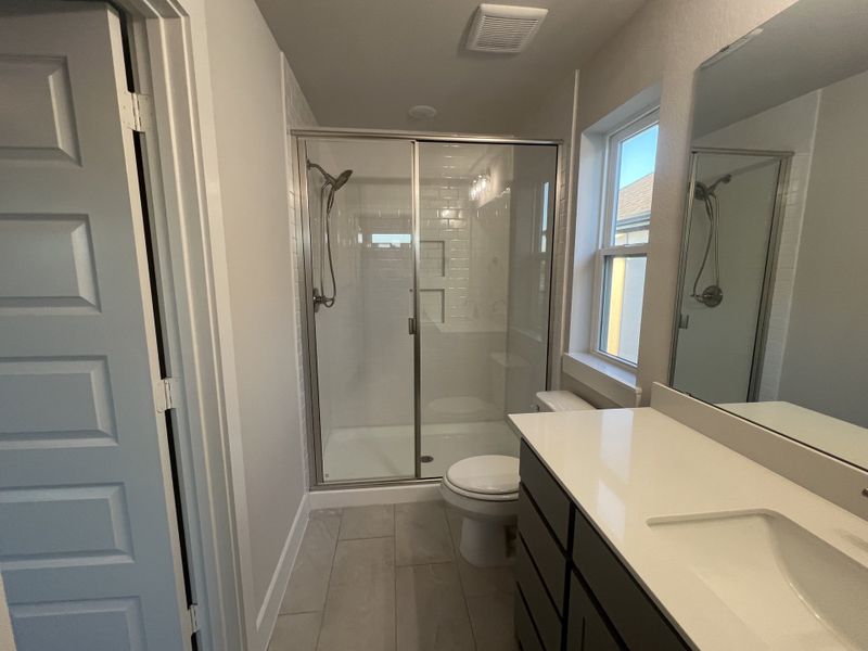 A modern bathroom featuring a spacious glass shower, sleek vanity, and ample natural light.