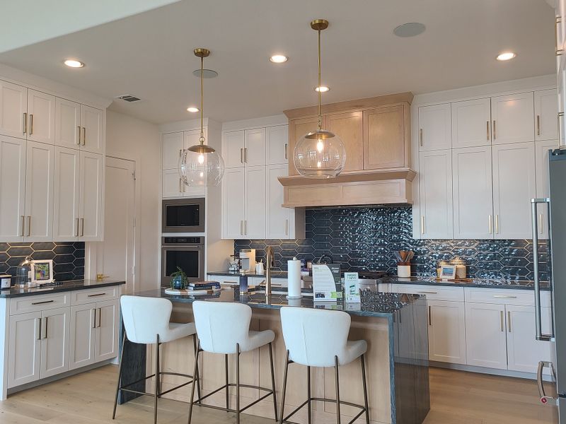 A modern kitchen with sleek white cabinetry, a stylish navy backsplash, and elegant pendant lighting over a central island. A modern kitchen with sleek white cabinetry, a stylish navy backsplash, and elegant pendant lighting over a central island.