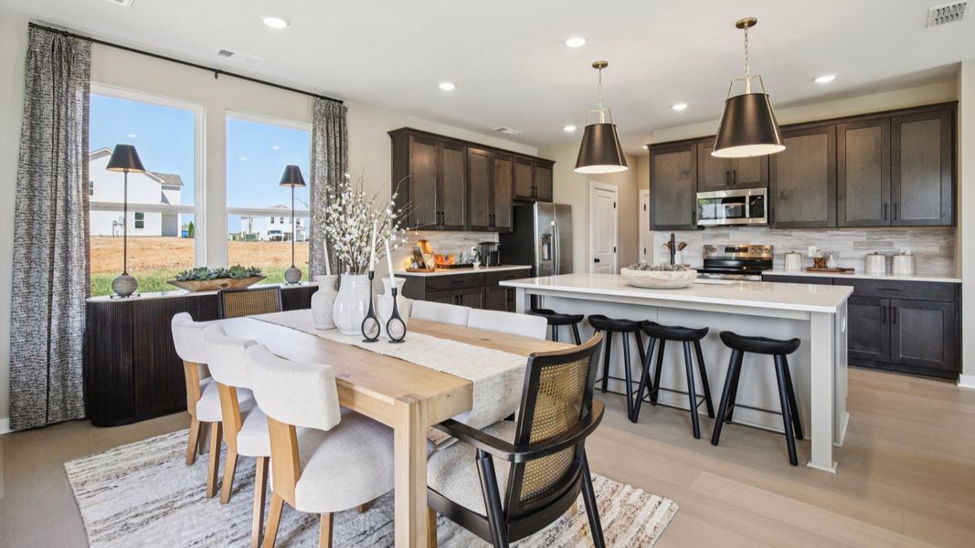 Expertly decorated dining area and kitchen with dark stained cabinets and modern color palette