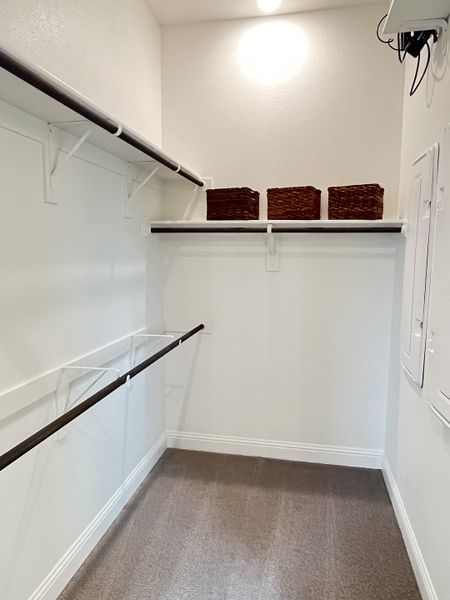 A spacious walk-in closet with sleek rails, carpeted floor, and wicker storage baskets for organized living.