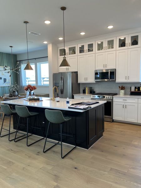 A modern kitchen with a sleek island, pendant lighting, and white cabinetry. A modern kitchen with a sleek island, pendant lighting, and white cabinetry.