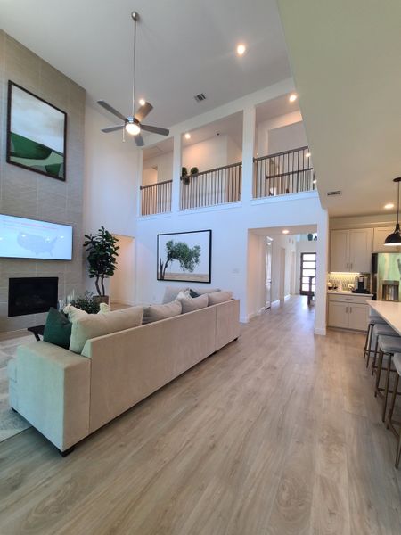 A modern living area with high ceilings, a beige sectional sofa, wood flooring, and elegant artwork for a cozy atmosphere.