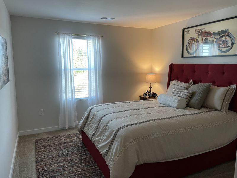 A cozy bedroom featuring a red tufted bed, soft lighting, and tasteful decor with a motorcycle theme. A cozy bedroom featuring a red tufted bed, soft lighting, and tasteful decor with a motorcycle theme.