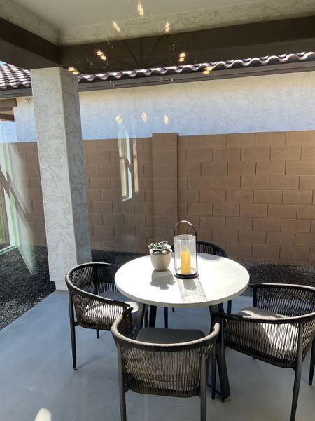 A cozy patio with modern wicker chairs and a round table, perfect for outdoor dining and relaxation.