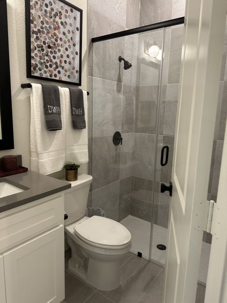 A modern bathroom featuring a glass shower, elegant gray tiles, and sleek fixtures for a chic and functional design.